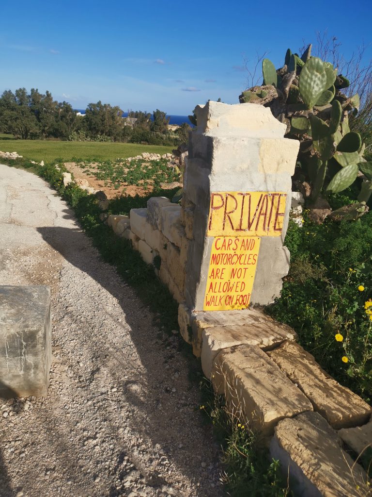 Sign on rock wall saying "PRIVATE cars and motorcycles are not allowed walk on foot"
