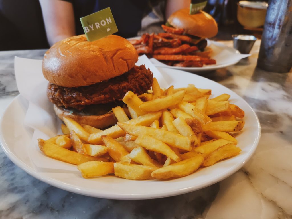 Photo of vegan chicken burger on white plate with skin-on fries