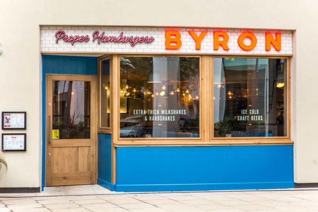 Exterior view of Byron Burger in Ipswich - blue and white bricked wall with wooden door and window frames